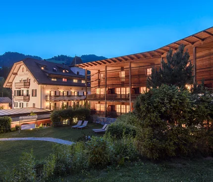 Hotel Ostaria Posta © Watzek Photografie Beleuchtete Hotelgebäude und Garten bei Dämmerung in den Bergen