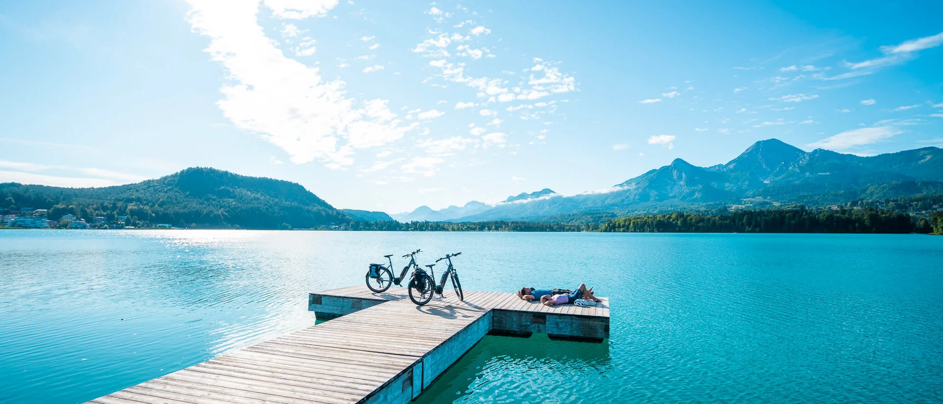 Brands © Kärnten Werbung - Gert Perauer People relaxing on pier with bikes by blue lake and mountains
