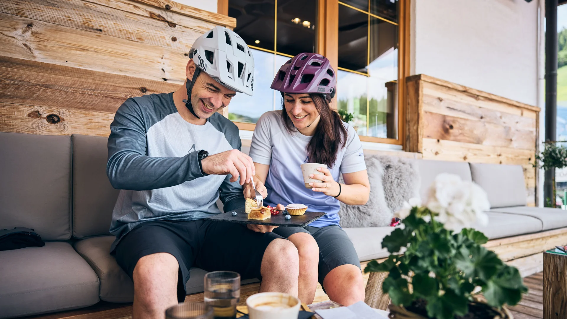 MTS Austria © Tobias Köhler Couple wearing bike helmets sharing cake and coffee on a patio