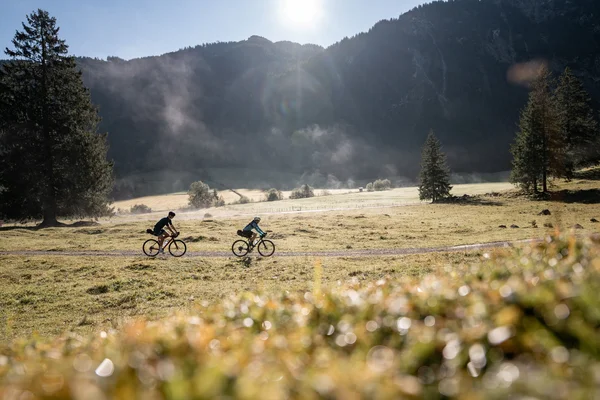 Gravelbike Holidays © Andreas Vigl Two cyclists riding on a trail in a mountainous landscape on a sunny day