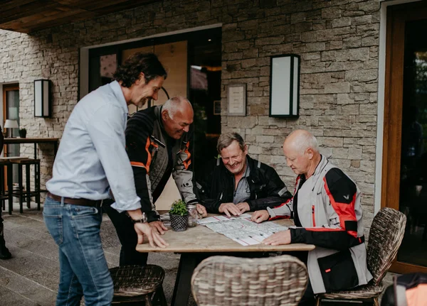 Agency Four men planning a trip using a map at an outdoor table