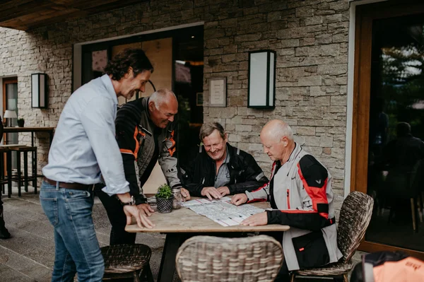 Four men planning a trip using a map at an outdoor table