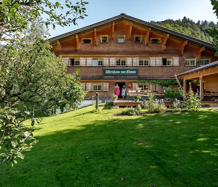 Gämsle Hotel, Wirtshaus & mehr © Raffael F. Lehner Traditionelles Gasthaus in einer grünen Landschaft mit zwei Personen an der Tür