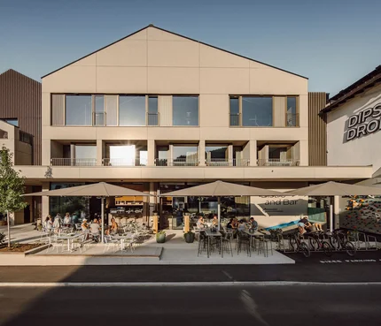 Dips&Drops - HOTEL · SPORTS · SPA · RESTAURANTS © Matthias Warter Außenansicht von Dips & Drops Bistro mit Terrasse und Gästen bei Sonnenlicht