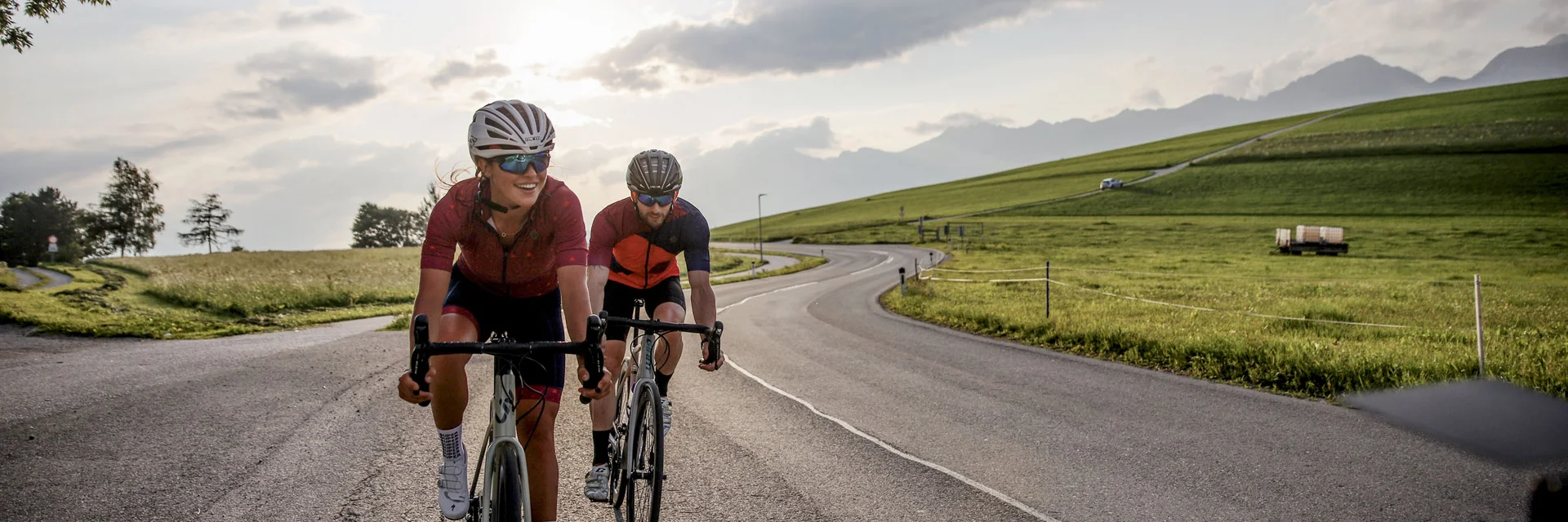 Two cyclists riding on a country road at sunset