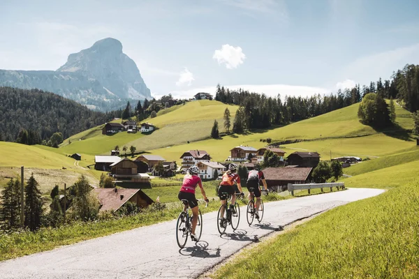 Destination development © Alex Moling Three cyclists ride on rural road in sunny valley with mountain backdrop