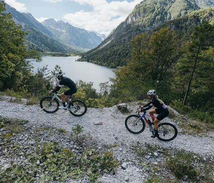Wörthersee © WRTG Fotograf Sam Strauss Zwei Radfahrer auf Bergweg mit See und Bergen im Hintergrund