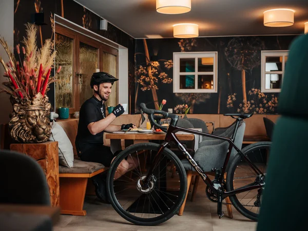 Bike Hotel © Martin Hoffmann Cyclist in black gear drinking coffee next to his bike in a café