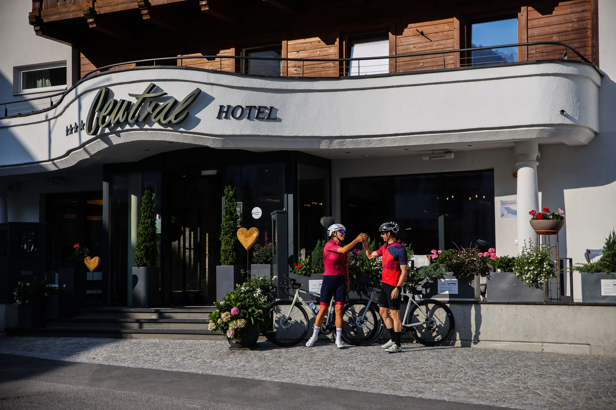 Zwei Radfahrer klatschen vor dem Central Hotel ab