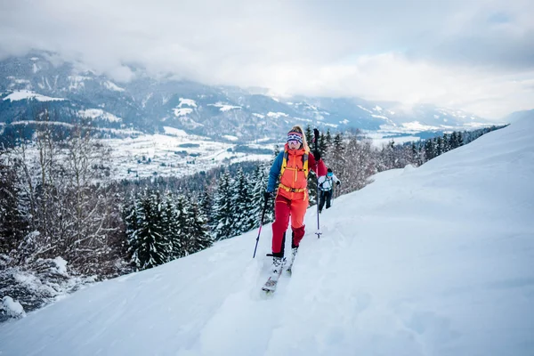 Skier ascending snowy mountain with panoramic valley view in background