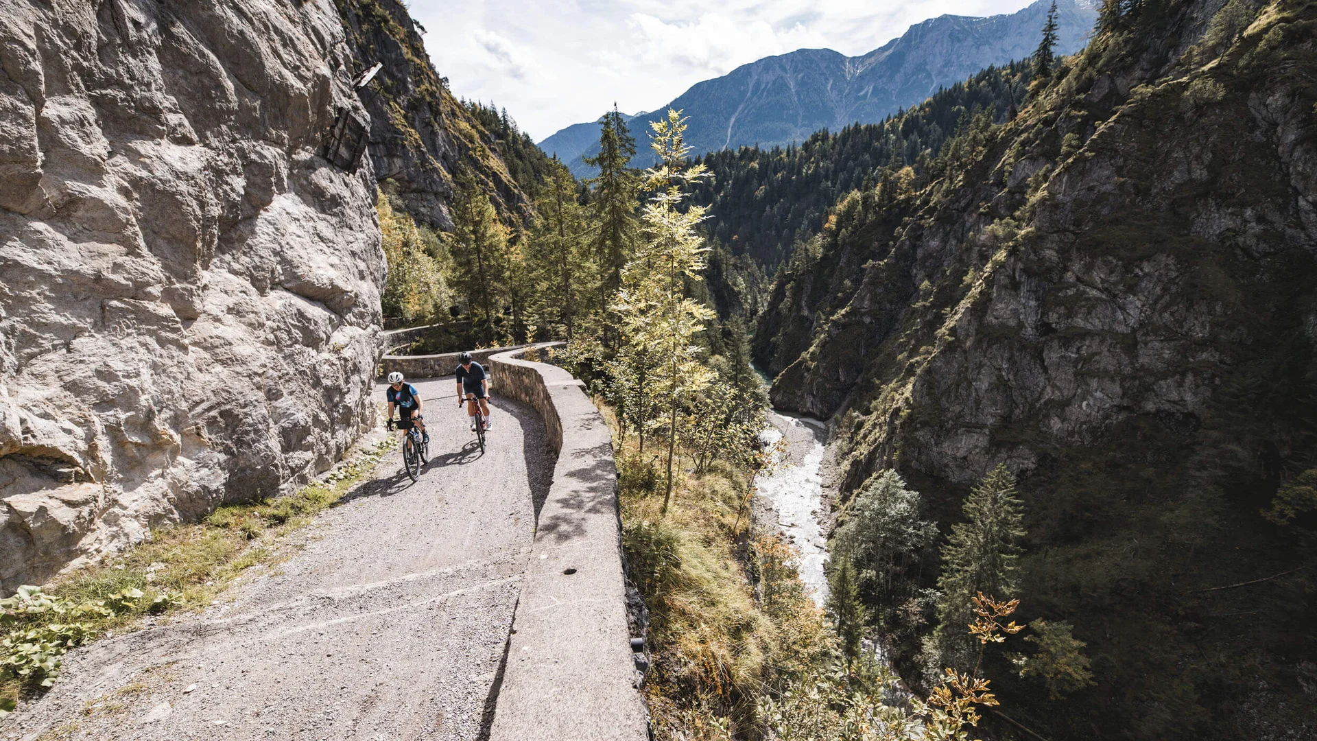 Destination development © Andreas Vigl Two cyclists on mountain trail beside river in forested canyon