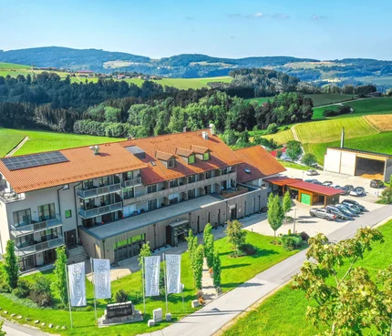 Landrefugium Obermüller © Stefan J. Wolf Photography Gebäude mit rotem Dach und Solarzellen umgeben von grüner Landschaft und Hügeln
