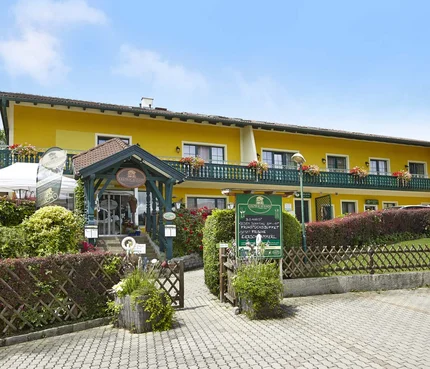 Landgasthof Krumbacherhof © Wiener Alpen Croy Gelbes Hotel mit grünem Eingang und Blumen an der Terrasse