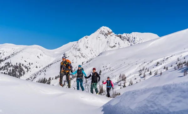 Cross-country skiing & ski touring hotel © TVB Großarltal / Peter Maier Four people snowshoe hiking in snowy mountains under clear blue sky