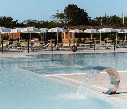 Natural Village Resort © Luigi Ventimiglia Moderner Pool mit Wasserfontäne und Liegestühlen unter weißen Sonnenschirmen