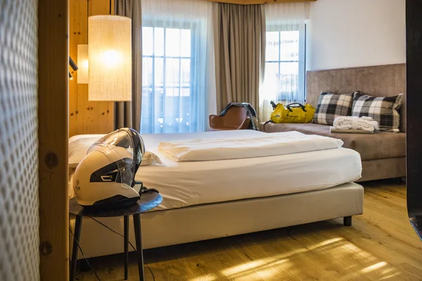 MoHo – Motorbike Hotels © Alexander Seger Cozy hotel room with single bed, chair, and motorcycle helmet on bedside table
