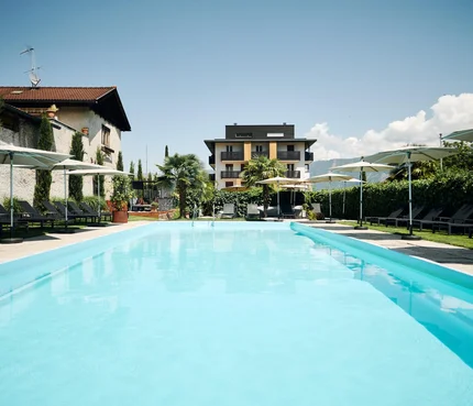 Traminerhof © Manuel Ferrigato Großer Pool mit Liegestühlen und Sonnenschirmen vor einem modernen Gebäude