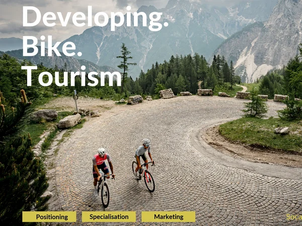 Destination development © Alain Rumpf - Bike Hotels e.V. Two cyclists on a winding cobblestone road in a forested alpine mountain landscape