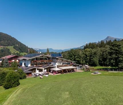Alpenhotel Landhaus Küchl © Michael Küchl Berghotel mit Solarpanels umgeben von Wiesen und Bergen bei klarem Himmel