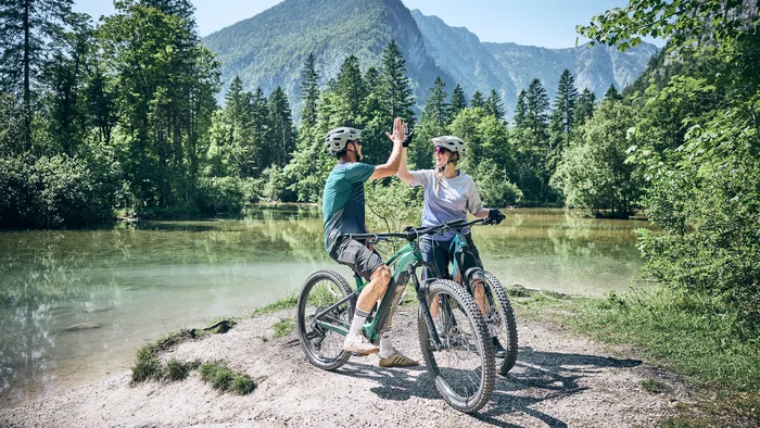 Careers © Tobias Köhler Two cyclists high-fiving by a mountain lake