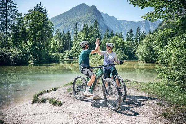 Destination development © Tobias Köhler Two cyclists high-fiving by a mountain lake