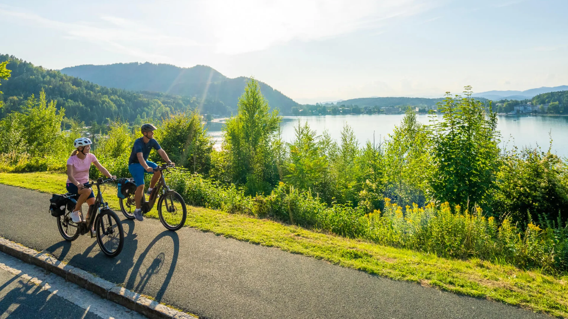 Destination development © Kärnten Werbung - Gert Perauer Two cyclists on road beside lake and trees on a sunny day