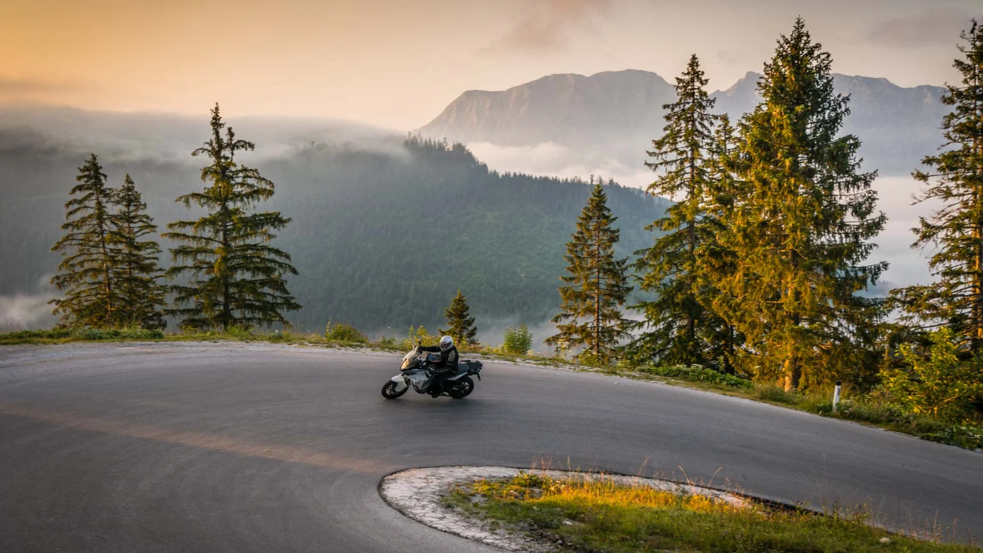 Brands © Moppetfoto.de Motorcyclist riding on winding mountain road at sunrise