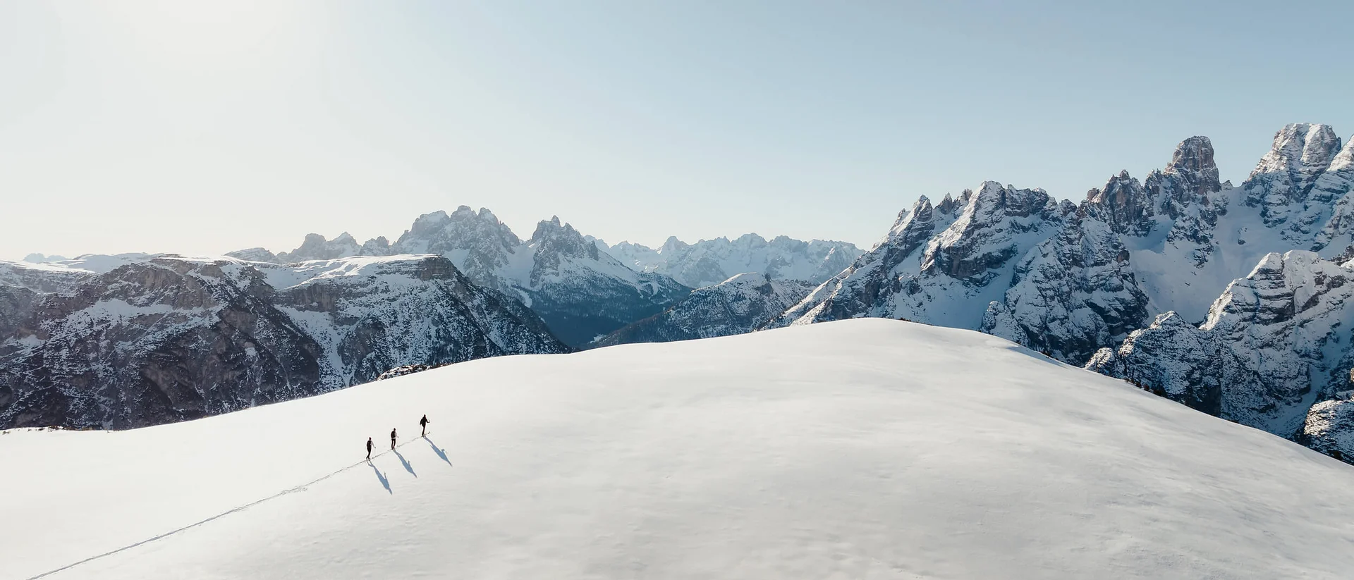 Careers © Alex Moling Three hikers walking on a snowy mountain with mountain range in background
