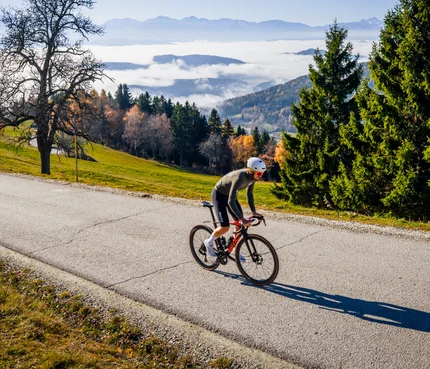 Mittelkärnten © Michael Stabentheiner Radfahrer fährt auf Bergstraße bei sonnigem Herbstwetter mit Nebel im Tal