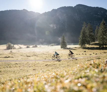 St. Anton am Arlberg © Andreas Vigl Zwei Radfahrer fahren auf einem Feldweg vor Bergkulisse bei Sonnenschein