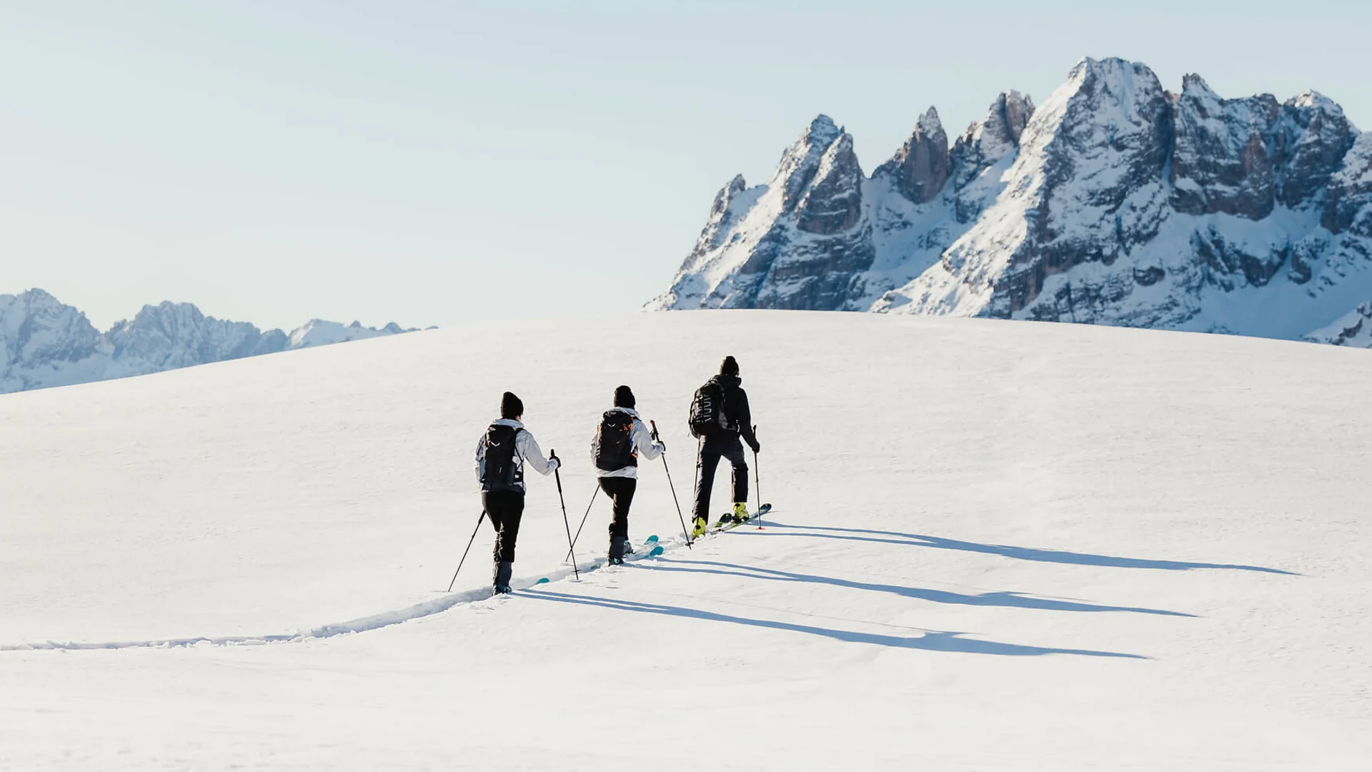 MTS Austria © Alex Moling Three skiers trekking on snowy hill under clear sky with mountain range in background