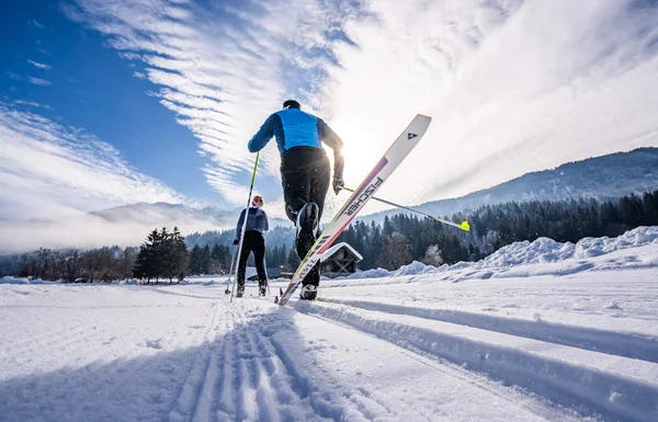 Two cross-country skiers on snowy trail in a winter landscape