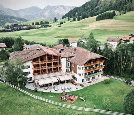 Hotel Bogner Hof © Hotel Bogner Hof GmbH & Co KG Blick auf ein Hotel im Bergtal mit grünen Wiesen und Bergen im Hintergrund