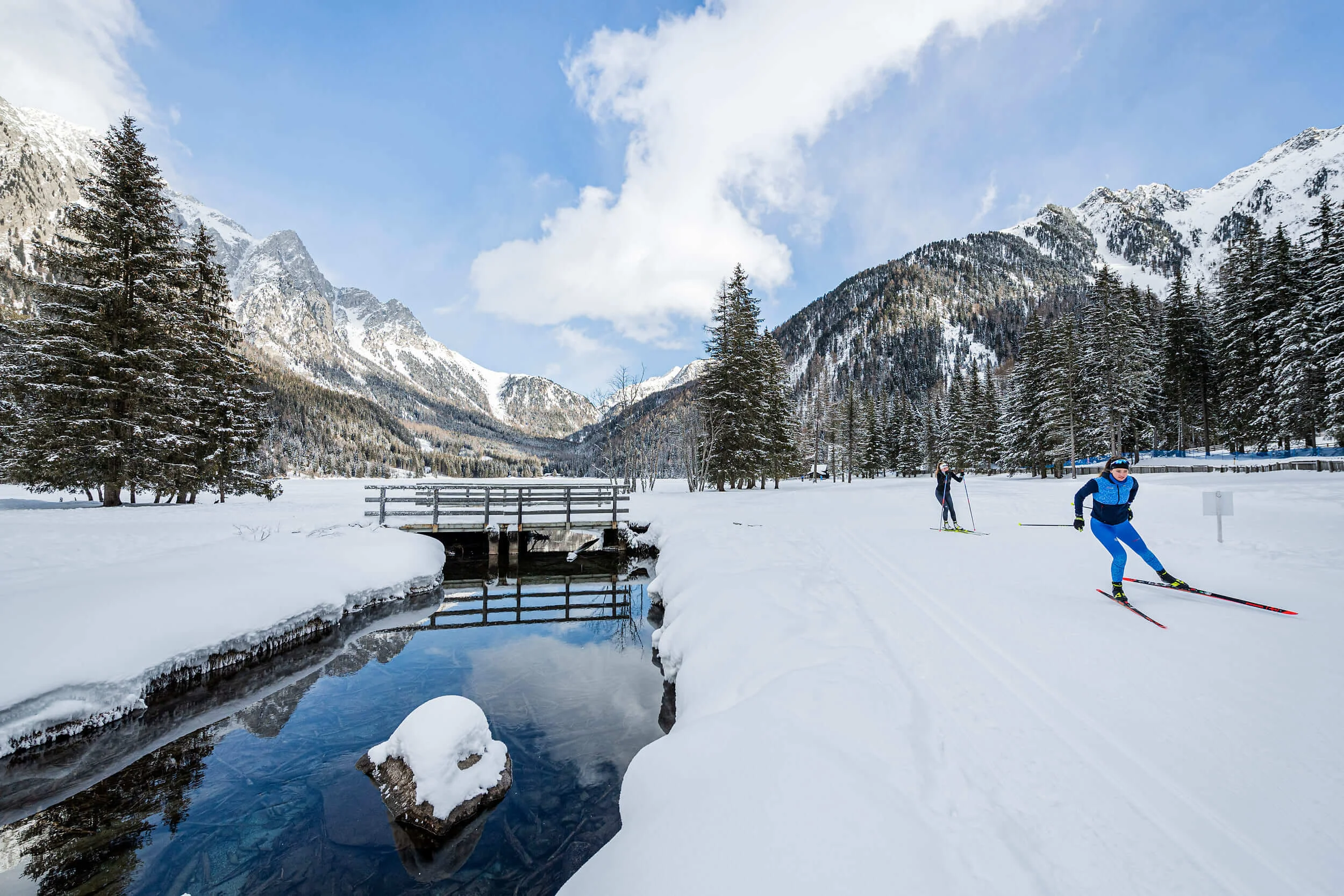 Langläufer unterwegs auf verschneiter Winterlandschaft mit Bergen und Wald